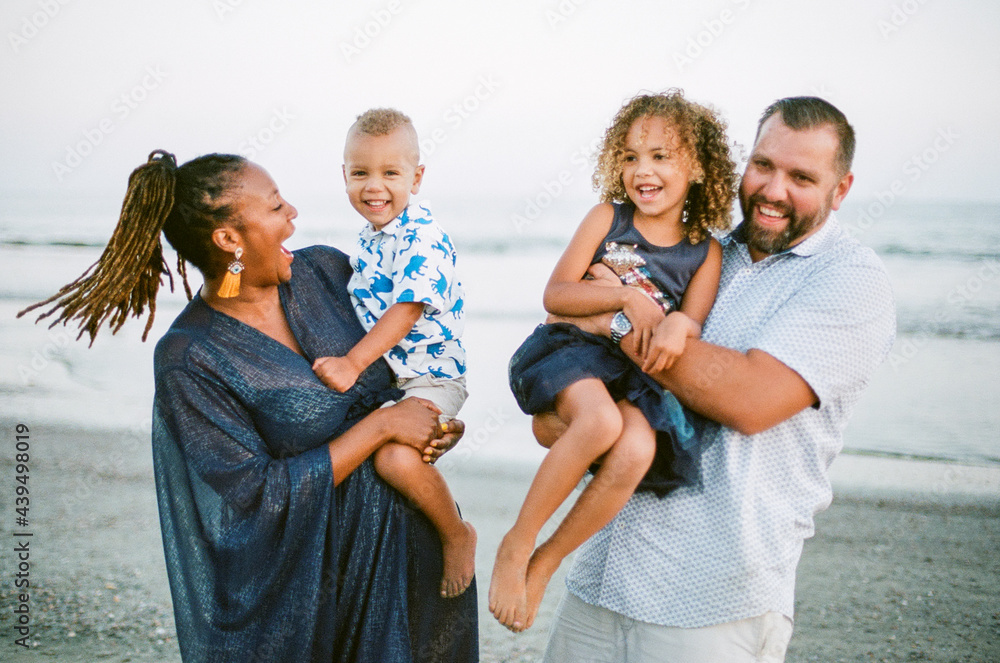 Laughing biracial family on beach at sunset Laughing biracial family on beach at sunset