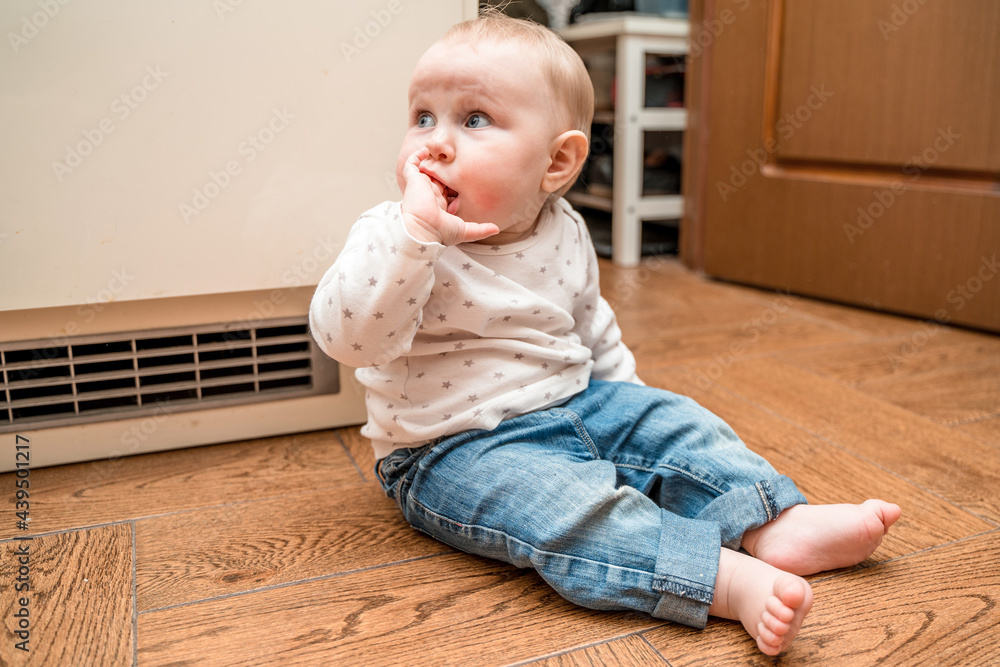 Adorable baby sitting on the floor of the house and looking away Adorable baby sitting on the floor of the house and looking away