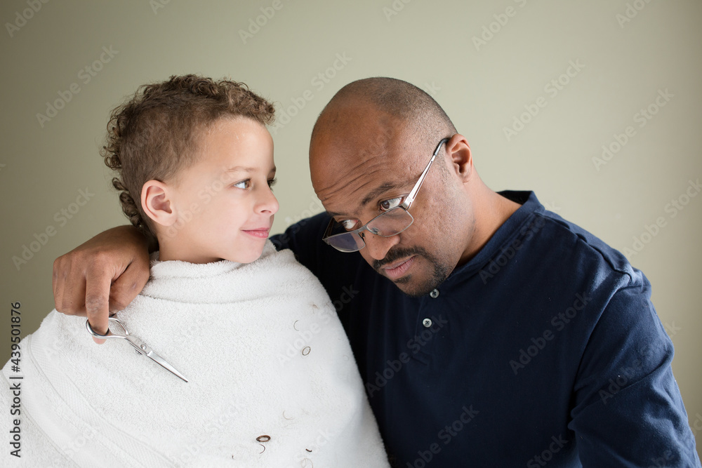 Father shows son his own balding head during haircut Father shows son his own balding head during haircut