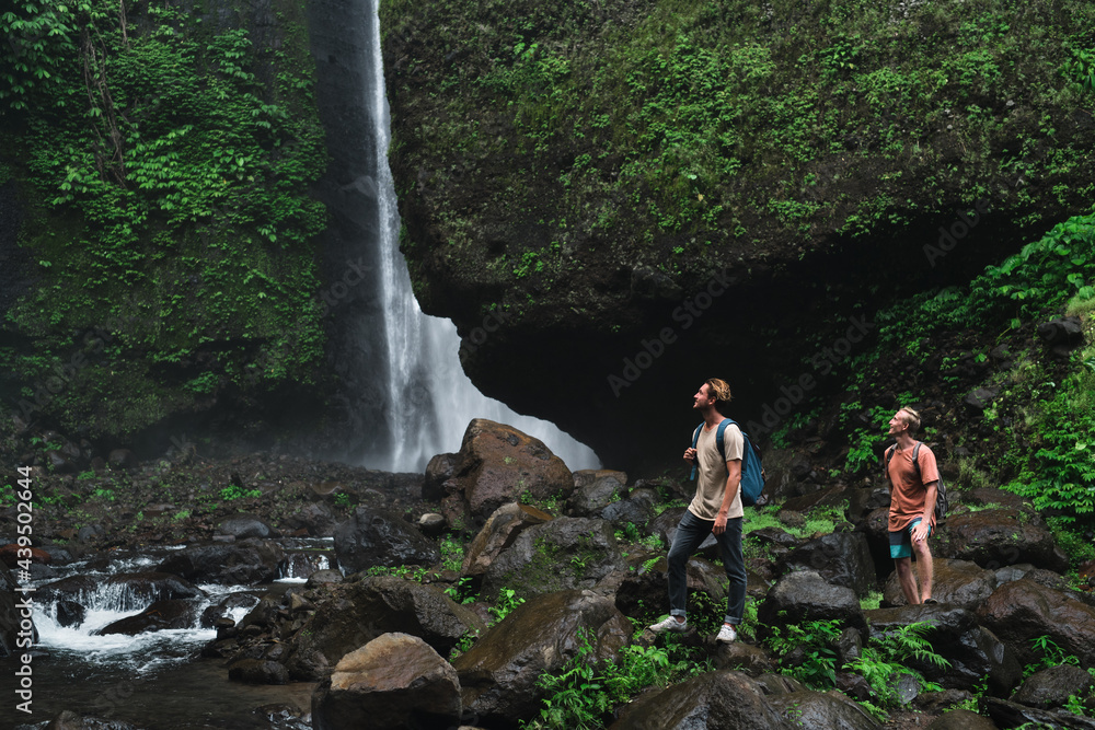 travelers stand by a waterfall in the jungle travelers stand by a waterfall in the jungle