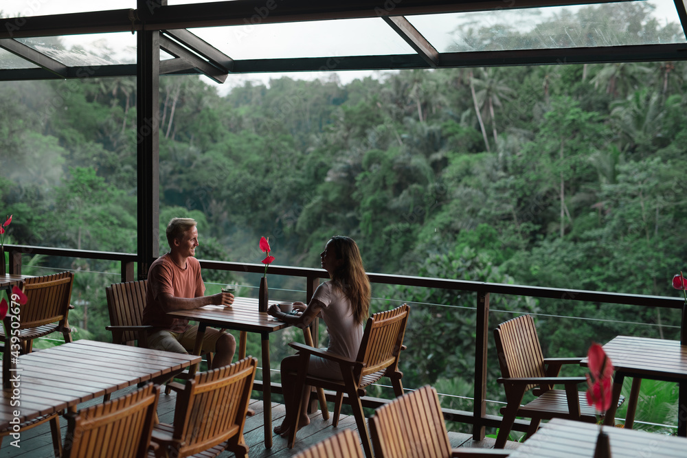 couple sitting at a table in a cafe overlooking the jungle couple sitting at a table in a cafe overlooking the jungle