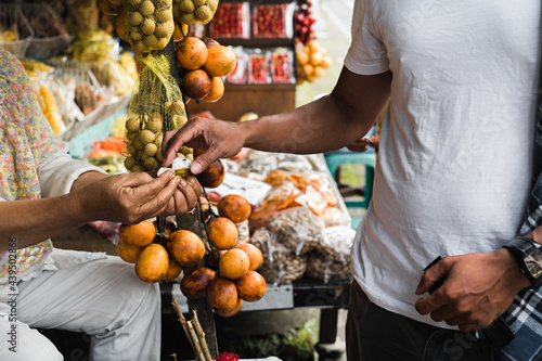 a tourist tastes tropical fruits from a seller in a local shop photo