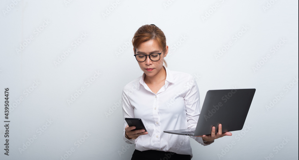 Happy woman using mobile phone while working with laptop. Smiling cool wearing eyeglasses messaging with smartphone.
Happy woman using mobile phone while working with laptop. Smiling cool wearing eyeglasses messaging with smartphone.
