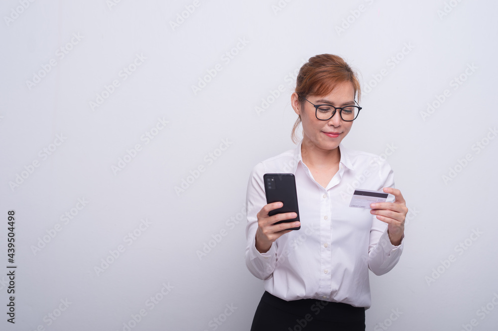 Portrait of smiling asian woman holding credit card and mobile phone isolated over white background Portrait of smiling asian woman holding credit card and mobile phone isolated over white background