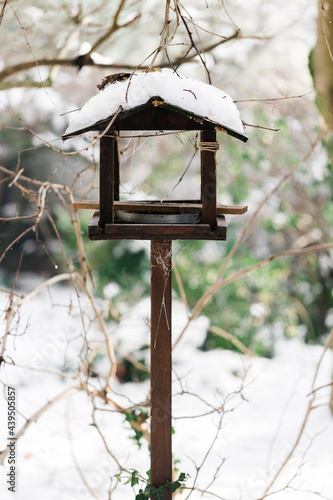 Snow on the roof of wooden bird feeder in garden photo