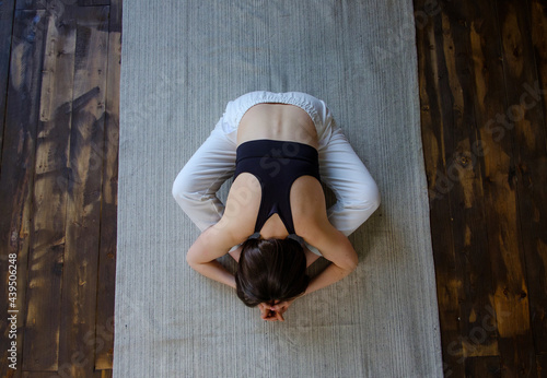 Top view young sporty woman hatha yoga instructor keep fit do gymnastics practice training bound angle posture seated Baddha Konasana pose on gym mat in wooden floor. Healthy lifestyle concept.