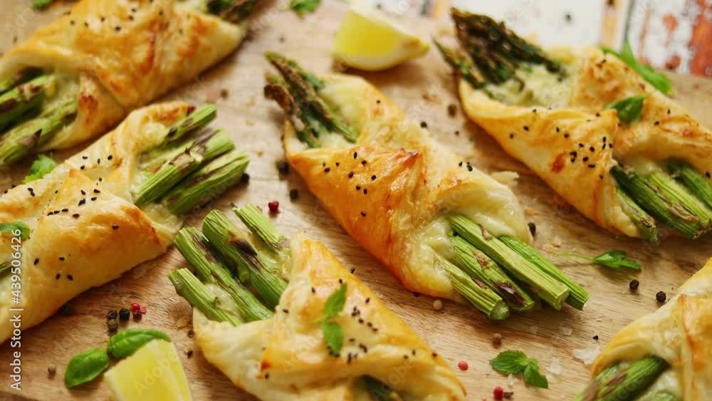 Baked green asparagus wrapped in puff pastry. Served on wooden board. With selective focus Baked green asparagus wrapped in puff pastry. Served on wooden board. With selective focus