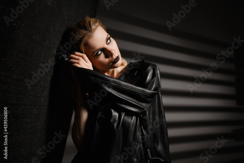 Beautiful girl with white hair in a black leather jacket on a black background