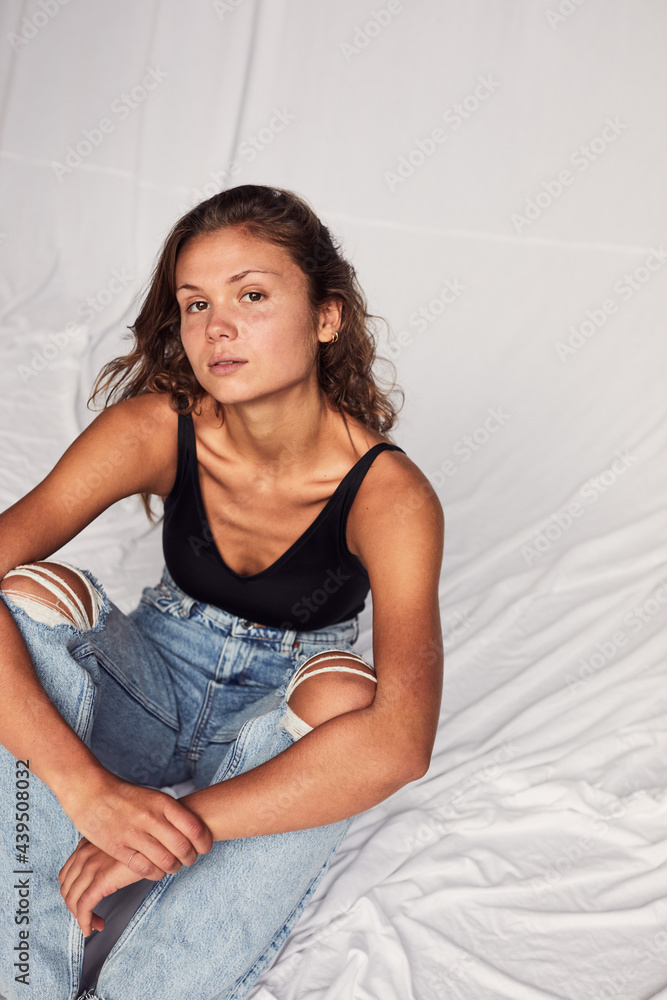 Woman sitting alone on a white backdrop Woman sitting alone on a white backdrop