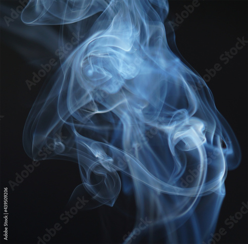 Flowing patterns of smoke from burning isolated black background.