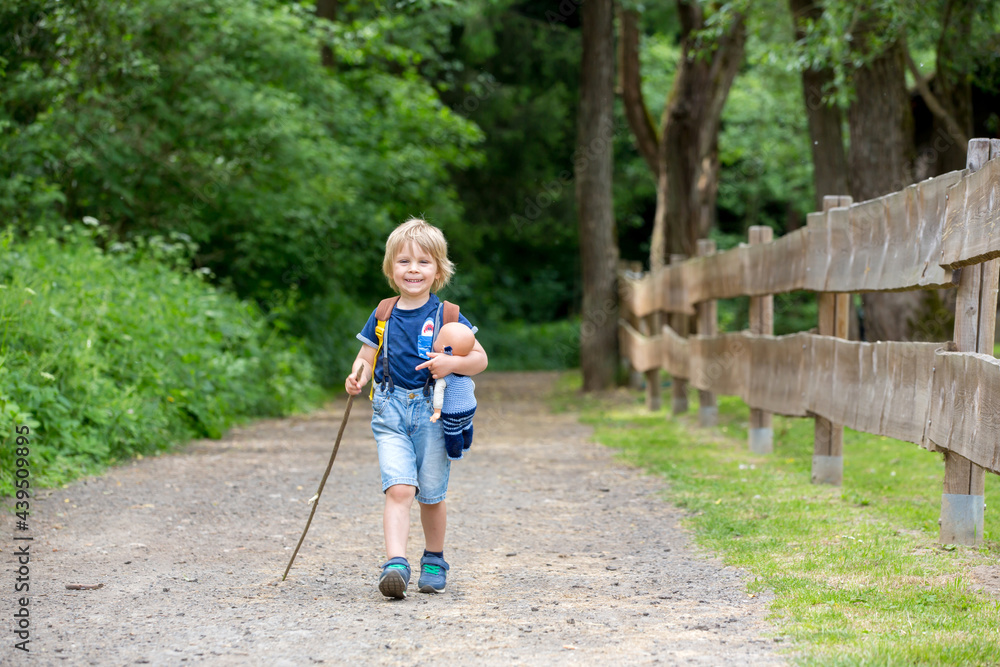 Little toddler boy, walking on little path next to a fence in the park, hiking Little toddler boy, walking on little path next to a fence in the park, hiking