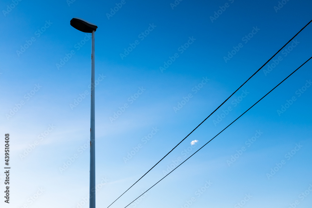 A lamppost with a small cloud between the wires. A lamppost with a small cloud between the wires.
