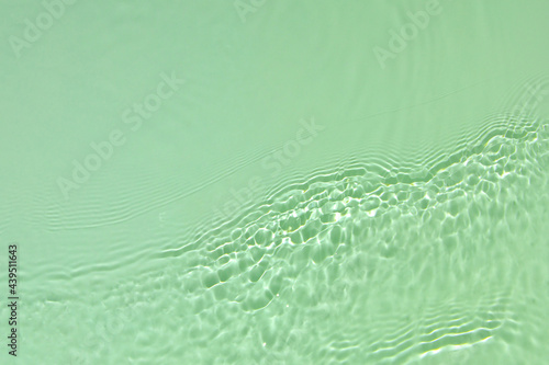 Green transparent clear water surface texture with ripples, splashes and bubbles Abstract summer nature background Mint colored waves in sunlight with copy space Cosmetic moisturizer micellar emulsion © Aleksandra Konoplya