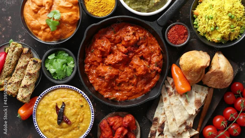 Various Indian dishes on a table. Spicy chicken Tikka Masala in iron pan Various Indian dishes on a table. Spicy chicken Tikka Masala in iron pan