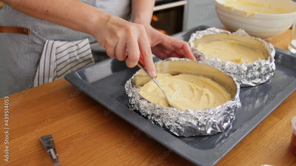 culinary, bake and cooking food concept - young woman baking cake and putting batter in baking dish on kitchen at home culinary, bake and cooking food concept - young woman baking cake and putting batter in baking dish on kitchen at home