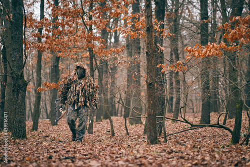 Bow hunter in ghillie suit photo