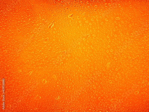 Water drops on orange background texture. backdrop glass covered with drops of water