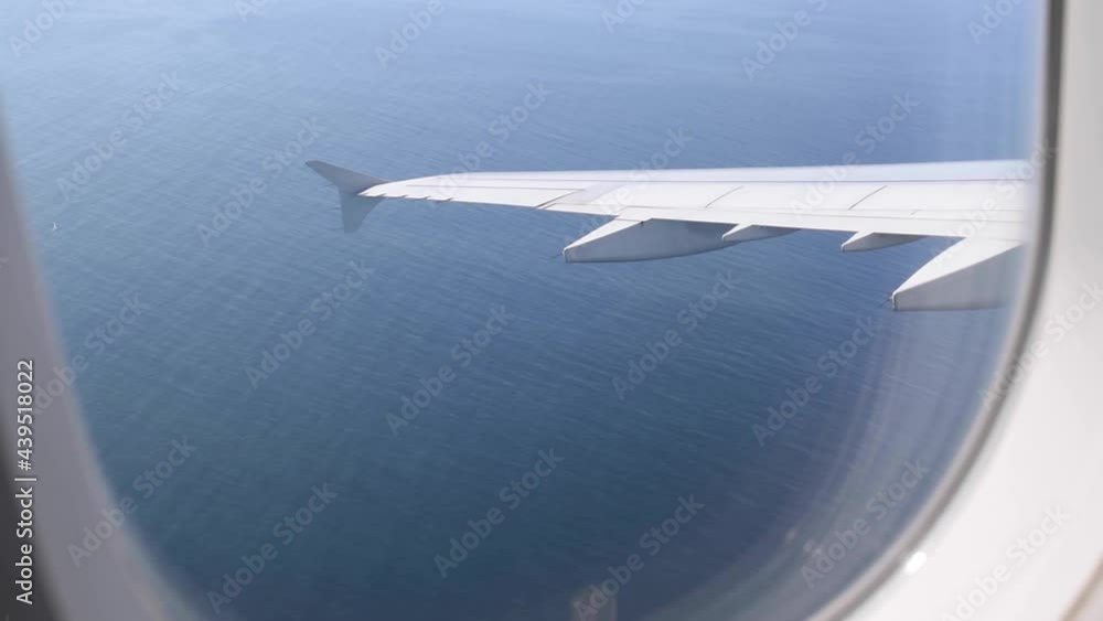 Scenic view from inside an Aircraft flying to a destination over the ocean while turning. Window seat in an aircraft while it is flying over the ocean Scenic view from inside an Aircraft flying to a destination over the ocean while turning. Window seat in an aircraft while it is flying over the ocean