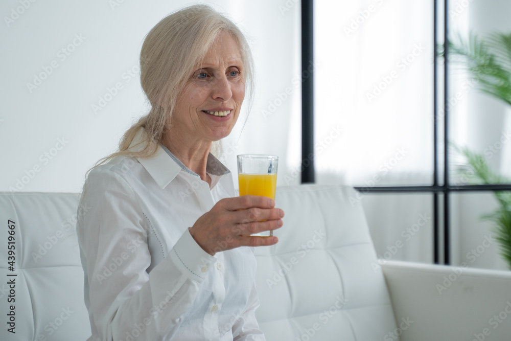 Senior woman drinking orange juice sitting on the couch, Old people retirement and healthy lifestyles Senior woman drinking orange juice sitting on the couch, Old people retirement and healthy lifestyles
