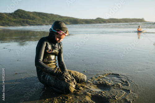 Girl in wetsuit covered in sand