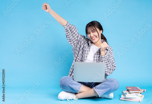 Asian female student with playful expression on blue background © Timeimage