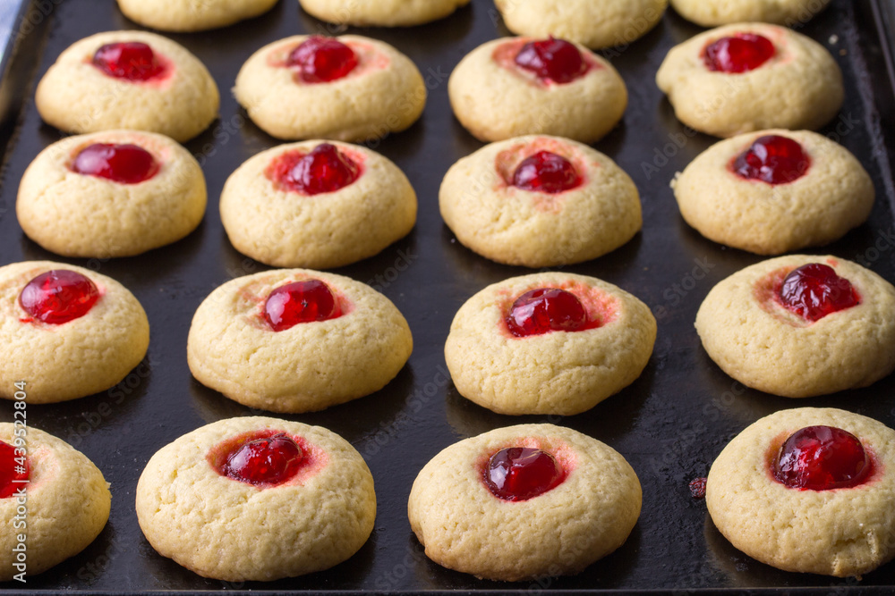 Cherry cookies on baking tray - delicious cherry topped cookies Cherry cookies on baking tray - delicious cherry topped cookies
