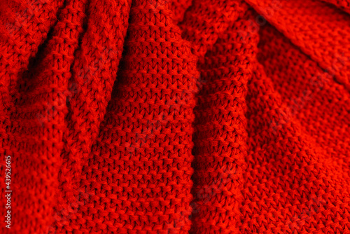 Texture of red knitted fabric close up. Wool jersey. Cozy red plaid top view. Knitted fabric close-up