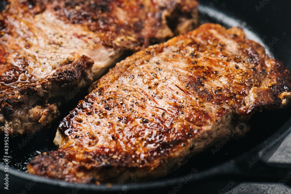 Closeup of NY Strip Steak cooking in an iron skillet Closeup of NY Strip Steak cooking in an iron skillet