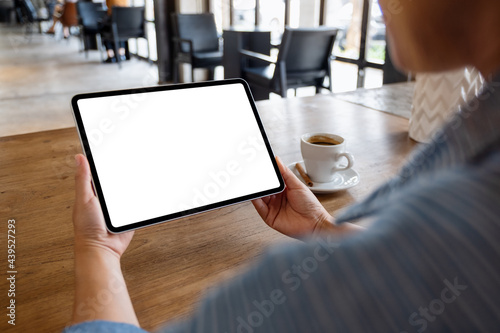 Mockup image of a woman holding digital tablet with blank white desktop screen in cafe