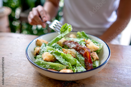 Closeup image of a woman eating a Caesar salad