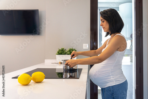 Young pregnant woman cooking in her home kitchen photo