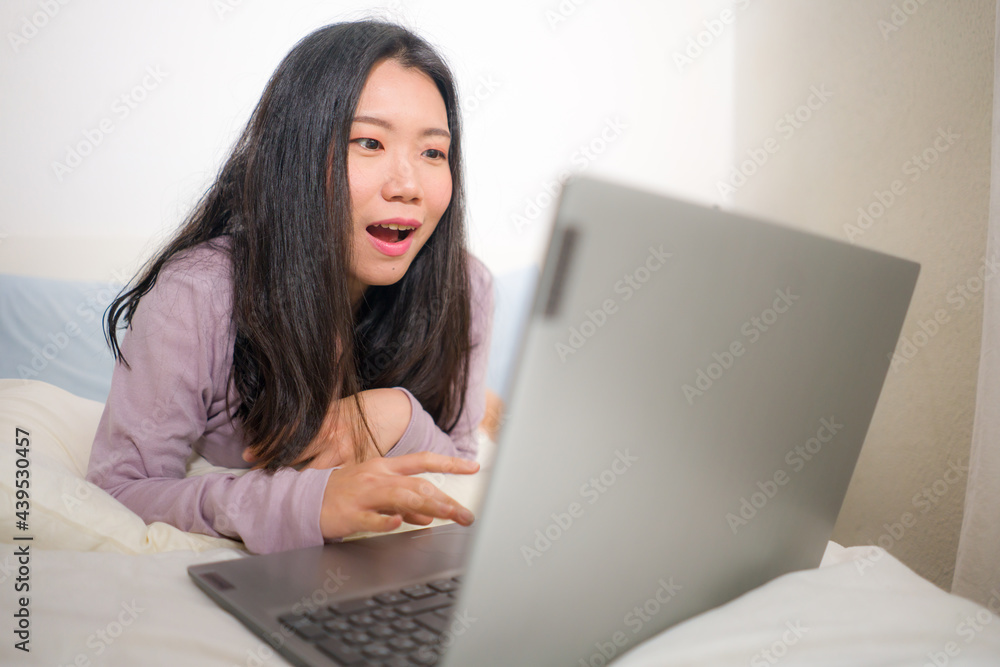 young beautiful Asian woman working with laptop on bed - lifestyle home portrait of young pretty and happy Korean student girl networking excited with computer on bedroom young beautiful Asian woman working with laptop on bed - lifestyle home portrait of young pretty and happy Korean student girl networking excited with computer on bedroom