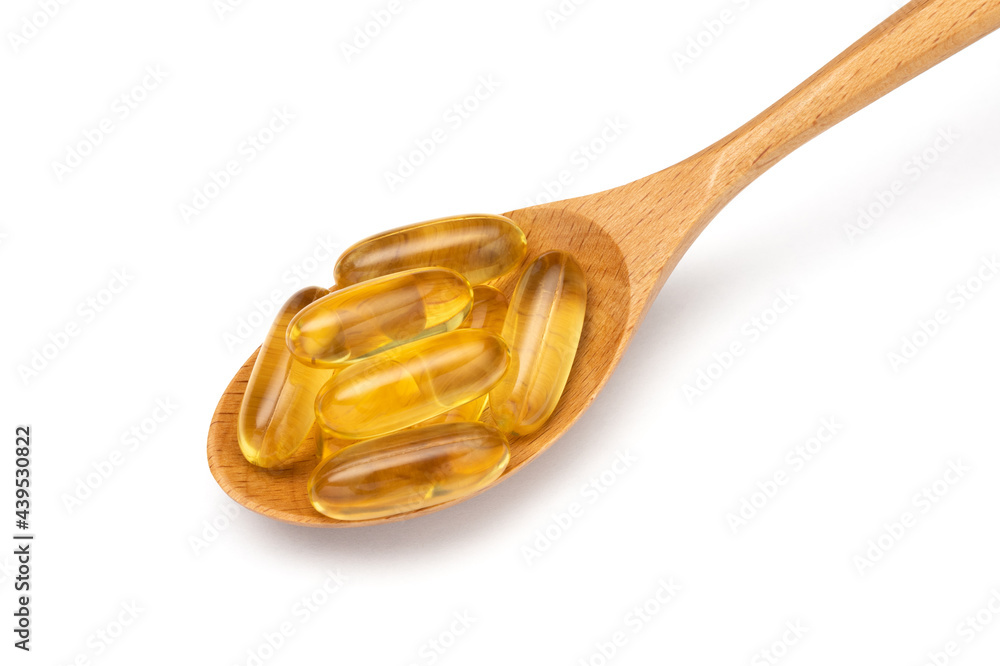Fish oil. Wooden spoon with Omega 3 capsules isolated on white background. Close up. Fish oil. Wooden spoon with Omega 3 capsules isolated on white background. Close up.