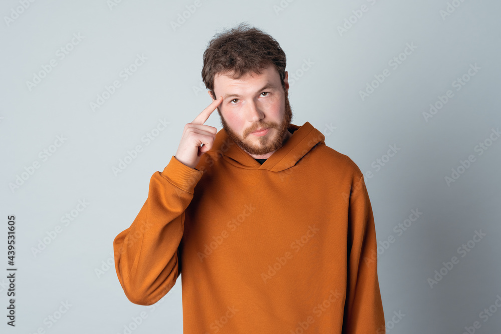 Confident bearded modern young man, pointing with finger at head. Concept of thinking. Be smart and think Confident bearded modern young man, pointing with finger at head. Concept of thinking. Be smart and think