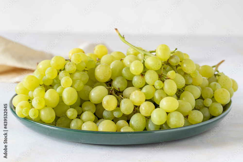 Ripe fresh green grapes on a green ceramic plate.