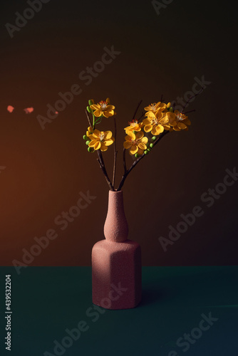 Ochna integerrima (apricot blossom) in a vase over color background with reflection photo