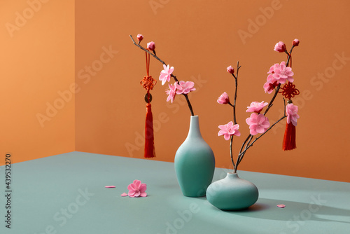 Flowering branches in vase with lucky knot isolated on color photo
