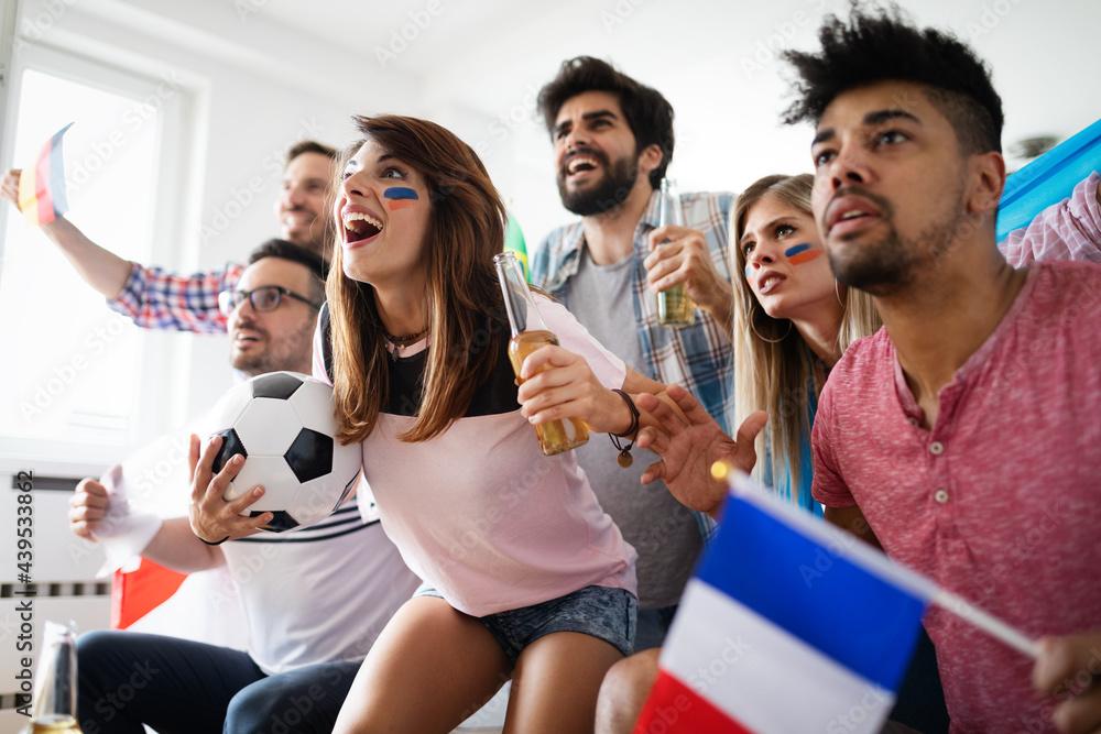 Obraz premium Happy group of young friends watching television and supporting their team