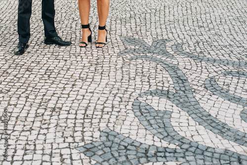 Male and female legs on Portuguese pavement