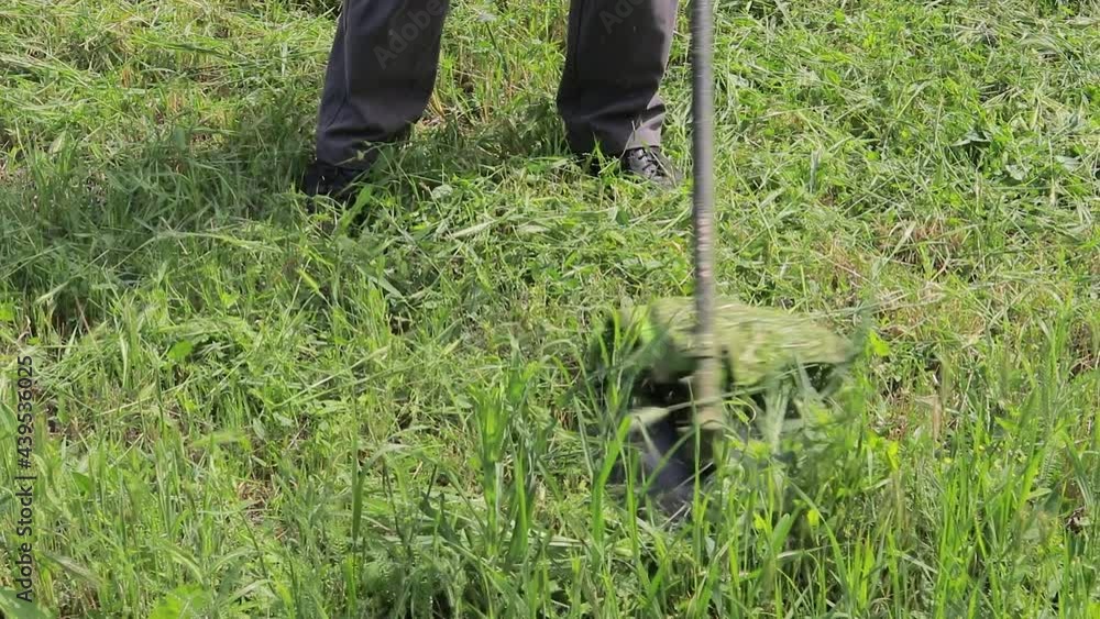 A man with an electric lawn mower mows the grass. Lawn mower blade knife spinning close-up. A man with an electric lawn mower mows the grass. Lawn mower blade knife spinning close-up.