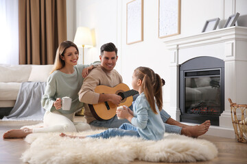 Happy family spending time together near fireplace at home