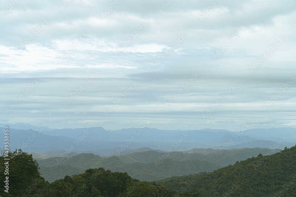 A photograph from a mountain peak in Asia. The early morning clouds that had not yet shined on the undulating mountains.