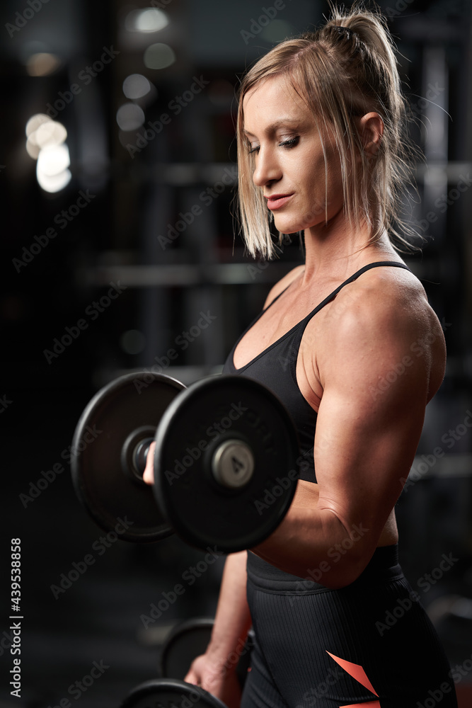Fitness girl doing biceps curls with dumbbells