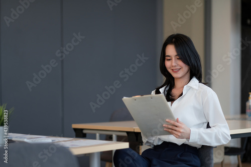 Portrait of successful young Asian businesswoman working with financial report at her office