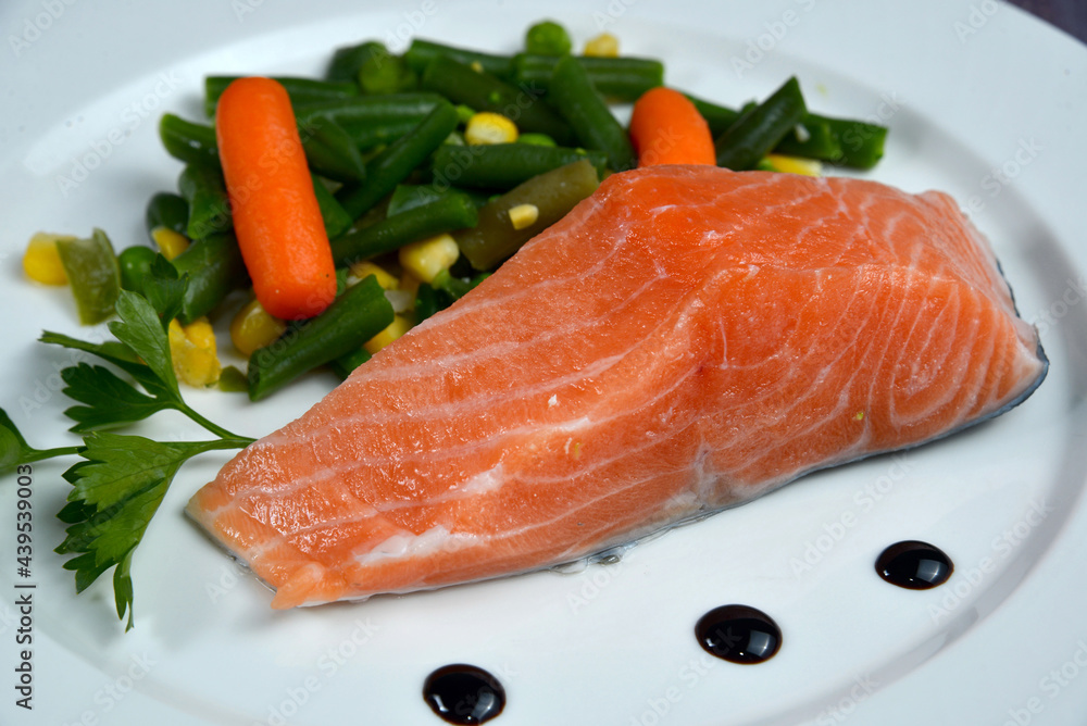 Fish dish - salmon with vegetables on white plate