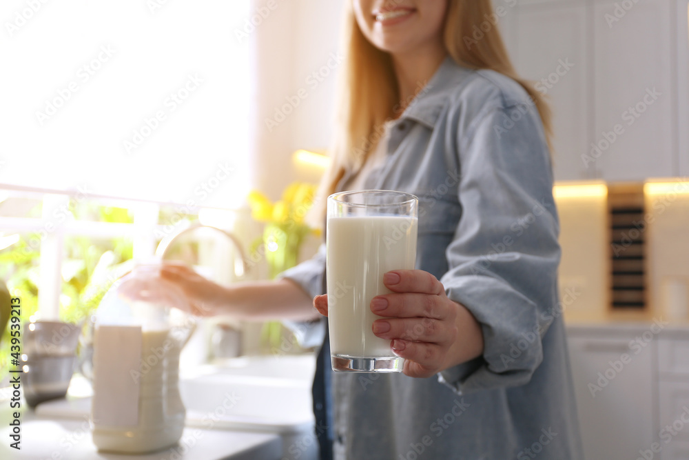 Young woman with gallon bottle of milk and glass at white countertop in kitchen, closeup Young woman with gallon bottle of milk and glass at white countertop in kitchen, closeup