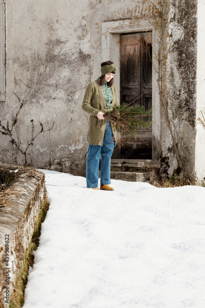 Young Woman Standing in the Snow Holding Branches Young Woman Standing in the Snow Holding Branches
