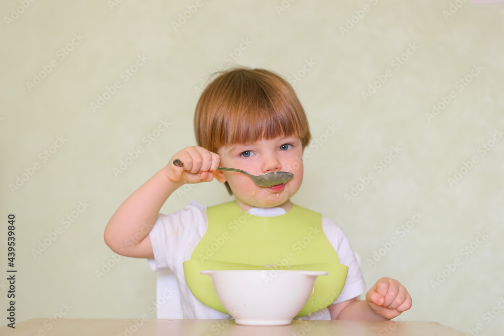 Happy cute infant baby boy spoon eats itself Happy cute infant baby boy spoon eats itself