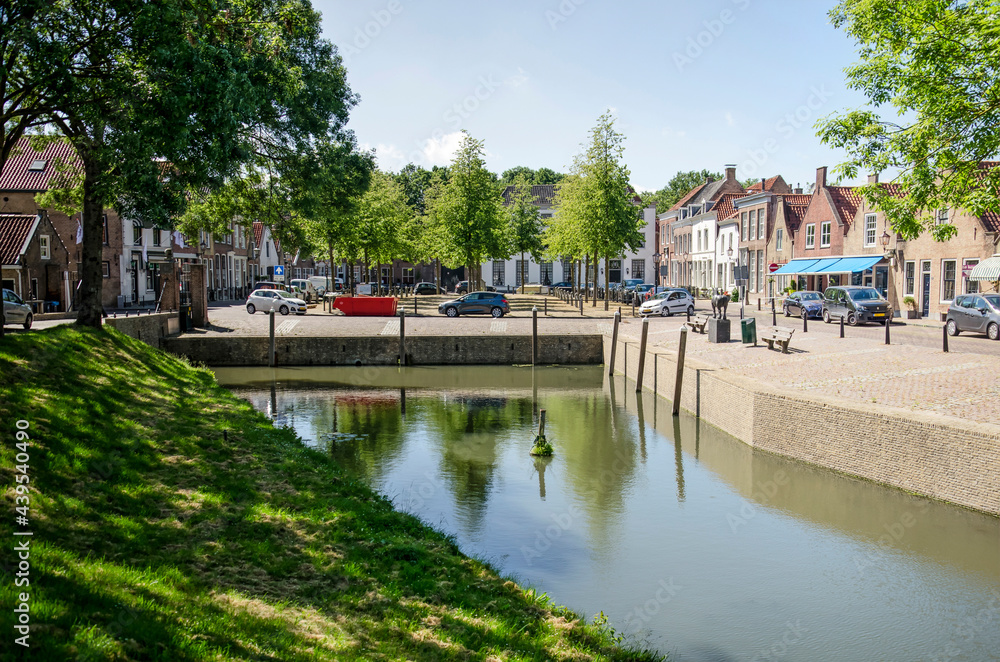 Geervliet, The Netherlands, June 12, 2021: view across the harbour towards the central market square with traditional houses and linden trees Geervliet, The Netherlands, June 12, 2021: view across the harbour towards the central market square with traditional houses and linden trees