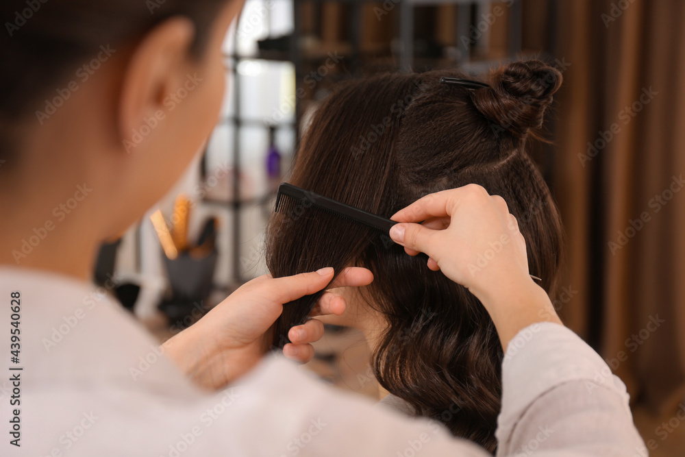 Naklejka premium Stylist working with client in salon, making hairstyle